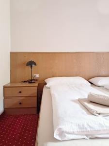 a bed with two white sheets and a night stand at haus e Apartment 3 in Lana