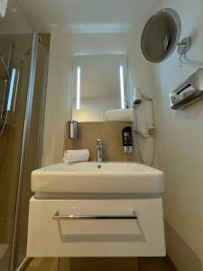 a bathroom with a white sink and a mirror at M&A Cityhotel Hildesheim in Hildesheim +42 photos
