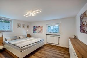 a white bedroom with a bed and two windows at Brunnerhof Urlaub auf dem Land in Hartenstein