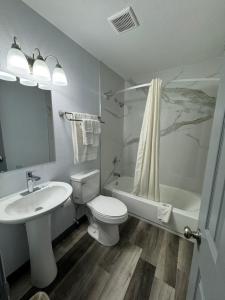 a bathroom with a sink and a toilet and a tub at Days Inn by Wyndham Gainesville Hospital - University Area in Gainesville
