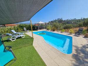a swimming pool with two lawn chairs next to it at Paradiesli in Castelo de Penalva