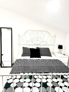 a white bedroom with a white bed with black pillows at Apartma Teja-Dekani in Dekani