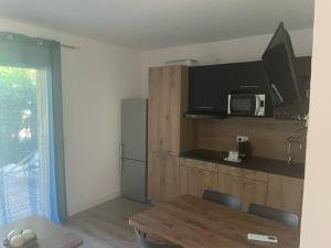 a kitchen with a table and a microwave and a table and chairs at Corse du sud Fiori di cala rossa T2 rez de jardin dans résidence piscine in Lecci