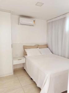 a white bedroom with a bed and a mirror at Porto de Galinhas - Apartamento 3 quartos a 30m do mar in Porto De Galinhas