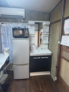 een kleine keuken met een spoelbak en een magnetron bij Hikari Kitaayase - 光莉 北綾瀬 - 浅草や上野へアクセス良好 MAX11名の和風宿 無料Wi-Fi in Tokyo +19 foto's