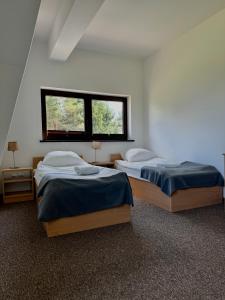 two beds in a room with two windows at WOSiR Szelment in Jeleniewo
