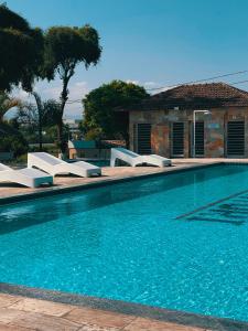 a swimming pool with white lounge chairs next to a house at O Paturi - Village Hotel Proximo Aparecida in Guaratinguetá