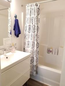 ein weißes Bad mit einem Waschbecken und einem Duschvorhang in der Unterkunft The Cottage on Claire in Point Roberts + 24 Fotos
