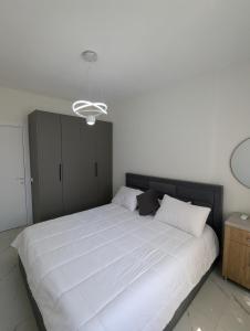 a bedroom with a large white bed with a black headboard at Mary's Beach Apartament Qerret in Golem +10 photos