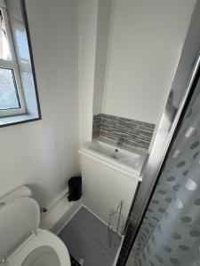 a white bathroom with a toilet and a sink at Amirs house reed ave in Kent +5 photos