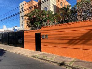 a large orange fence with plants on top of it at Aptos 1 quarto Ar Saraiva in Uberlândia