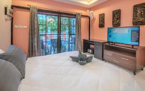 a bedroom with a large white bed with a flat screen tv at Villa Madee near Walking Street and beaches in Pattaya South