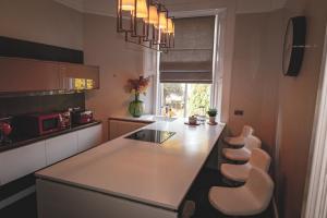 a kitchen with a white counter and stools at Stirling Apartment - A Central Scotland Base in Stirling