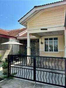 a house with a black fence and an umbrella at Rumah Tamu by Perdana Hōmes for Múslim only in Sungai Petani