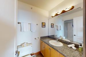 Un baño con lavabo, inodoro y espejo. en Tree Tops 12, en Big White 22 fotos más