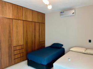 a bedroom with two beds and a wooden cabinet at Ejecutiva Frac privado Nueva alberca 50MB Factura in La Orilla +27 photos