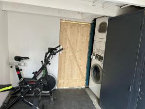 a garage with a door and a bike in front of a washing machine at Reve Divin T2 en R/C parking-bagagerie-salle sport-barbecue in Lourdes +3 photos
