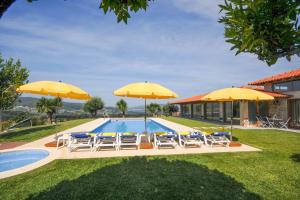 una piscina con sedie e ombrelloni accanto a una casa di Casa da Pedra ad Aborim
