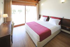 una camera da letto con un letto grande e una grande finestra di Casa da Pedra ad Aborim Altre 22 foto