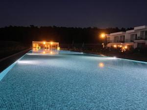 a large swimming pool lit up at night at Oikos Sani Suites in Sani Beach
