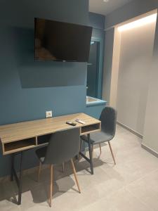 a room with a desk with two chairs and a tv on the wall at MP luxury houses Ι2 in Larisa