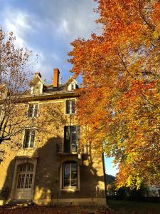 un grand bâtiment en pierre avec un balcon et des feuilles d'automne dans l'établissement Studio Hyper-Centre Villa Isabelle, à Allevard