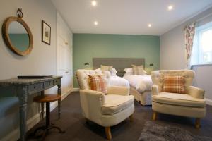 a bedroom with a bed and two chairs and a mirror at The Trout at Tadpole Bridge in Faringdon