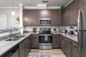 Una cocina con electrodomésticos de acero inoxidable y gabinetes de madera. en Long-term Stays in Greensboro 1 BD 1 BA, en Greensboro