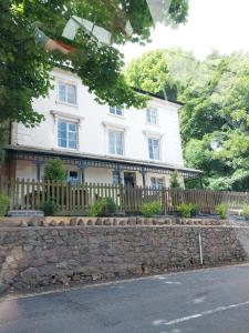 a white house with a fence and a stone wall at Stylish 2-bed Duplex Stunning Malvern views Peaceful Getaway in Malvern Wells