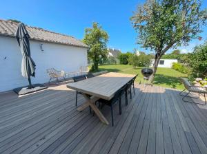eine Holzterrasse mit einem Picknicktisch und einem Sonnenschirm in der Unterkunft Grande maison familiale, plage in Pénestin