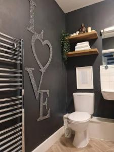 ein Bad mit WC und ein Herzschild an der Wand in der Unterkunft Stylish Apartment near Tower Bridge in London