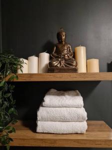 ein Regal mit einer Buddha-Statue und Handtüchern darauf in der Unterkunft Stylish Apartment near Tower Bridge in London