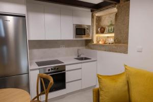 a kitchen with white cabinets and a stainless steel refrigerator at Casa Soledá e Pepa in Outes +18 photos