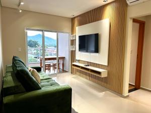 a living room with a green couch and a television at Aptos perfeito para suas férias, surpreenda a todos in Ubatuba