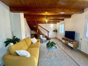 - un salon avec un canapé jaune et une télévision dans l'établissement Jolie maison entièrement rénovée à la montagne, à Villar-Saint-Pancrace