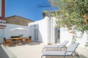 a patio with chairs and a table with an umbrella at Sanlucar Centro - Apartamento 5 in Sanlúcar de Barrameda