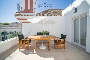 a table with chairs and an umbrella on a balcony at Sanlucar Centro - Apartamento 5 in Sanlúcar de Barrameda