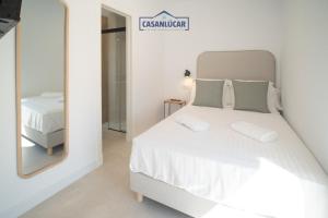 a bedroom with a white bed and a mirror at Sanlucar Centro - Apartamento 5 in Sanlúcar de Barrameda