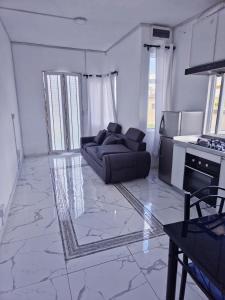 Una sala de estar con un sofá y una cocina. en Couple Perfect - Lovely New 1-Bedroom Apartment, en Réunion