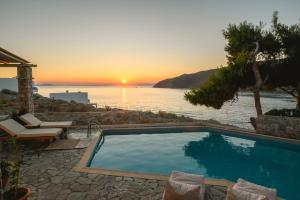 a swimming pool with a view of the ocean at sunset at Yperia Hotel in Aegiali