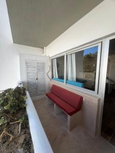 a red bench in a room with a window at Edificio RexII in Es Pujols