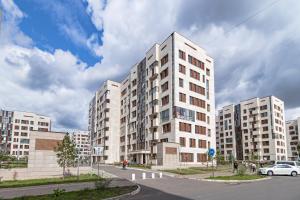 a tall white building with cars parked in front of it at Apartment near EXPO-2017, Hilton in Taldykolʼ