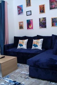a living room with a blue couch and pictures on the wall at EDENVILLE HOMES-1 Bedroom Apartment Kiambu Road, Thindigua in Nairobi