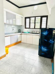 Una cocina con gabinetes blancos y un refrigerador negro. en Rahima Villa 2BHK first floor, en Ernakulam