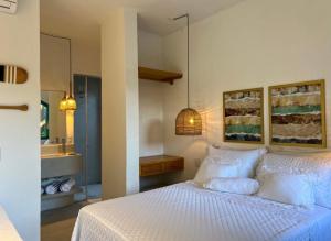 a bedroom with a white bed and a bathroom at Flô Casa Hotel in Trancoso