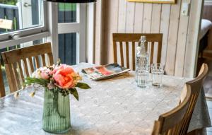 a table with a vase of flowers and a bottle at Beautiful Home In Juelsminde With Sauna in Sønderby