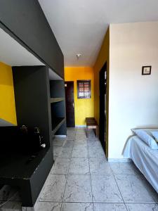 a bedroom with a bed and yellow walls at Pousada Morada Dusanjos in Caraguatatuba