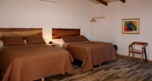 a hotel room with two beds and a chair at Estancia Los Amigos Valle de Guadalupe in Valle de Guadalupe