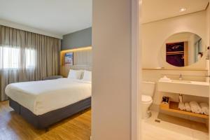a hotel room with a bed and a sink at Hampton by Hilton Guarulhos Airport in Guarulhos