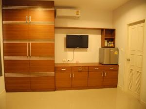 a room with wooden cabinets and a tv in a room at Green House Phuket in Ban Pa Khlok